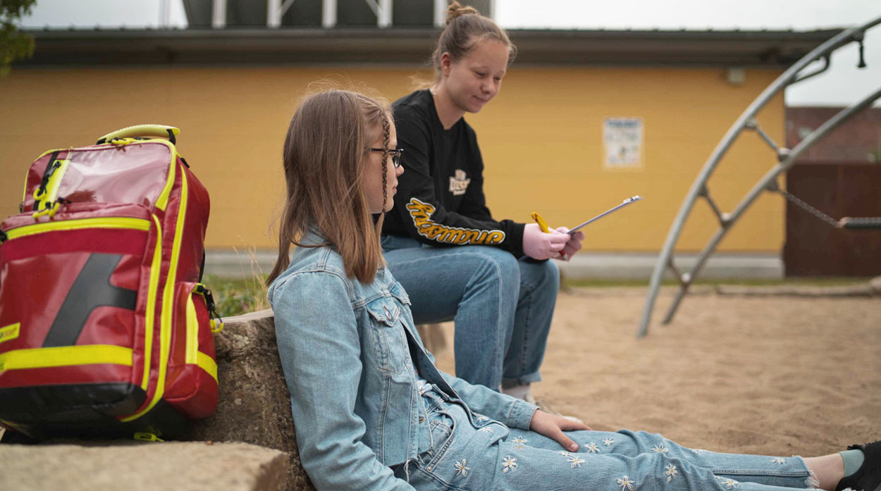ESG-Schulsanitaeter-draussen im Sand sitzen und reden